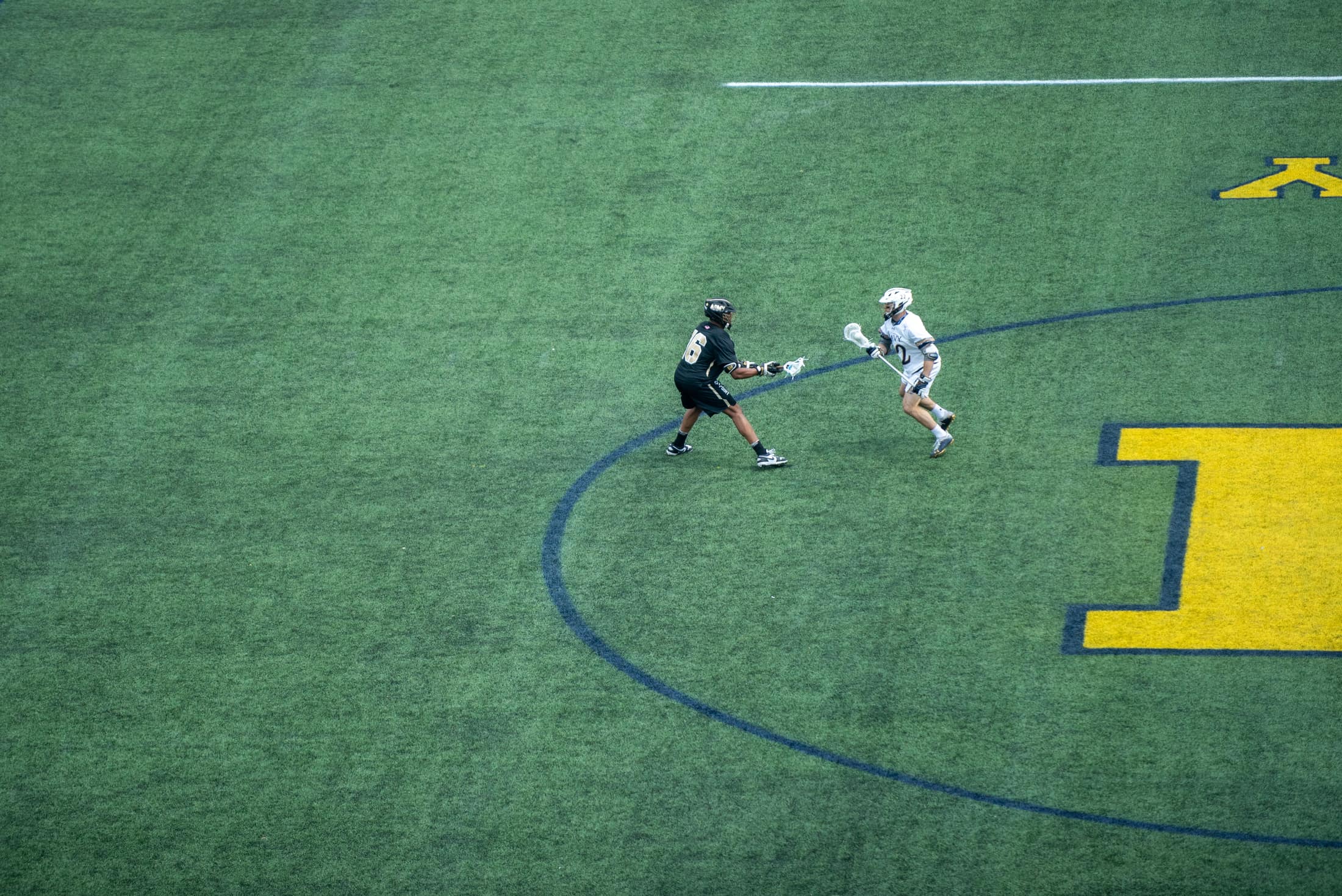 Two players contesting the ball at midfield in the Navy–Army lacrosse rivalry game